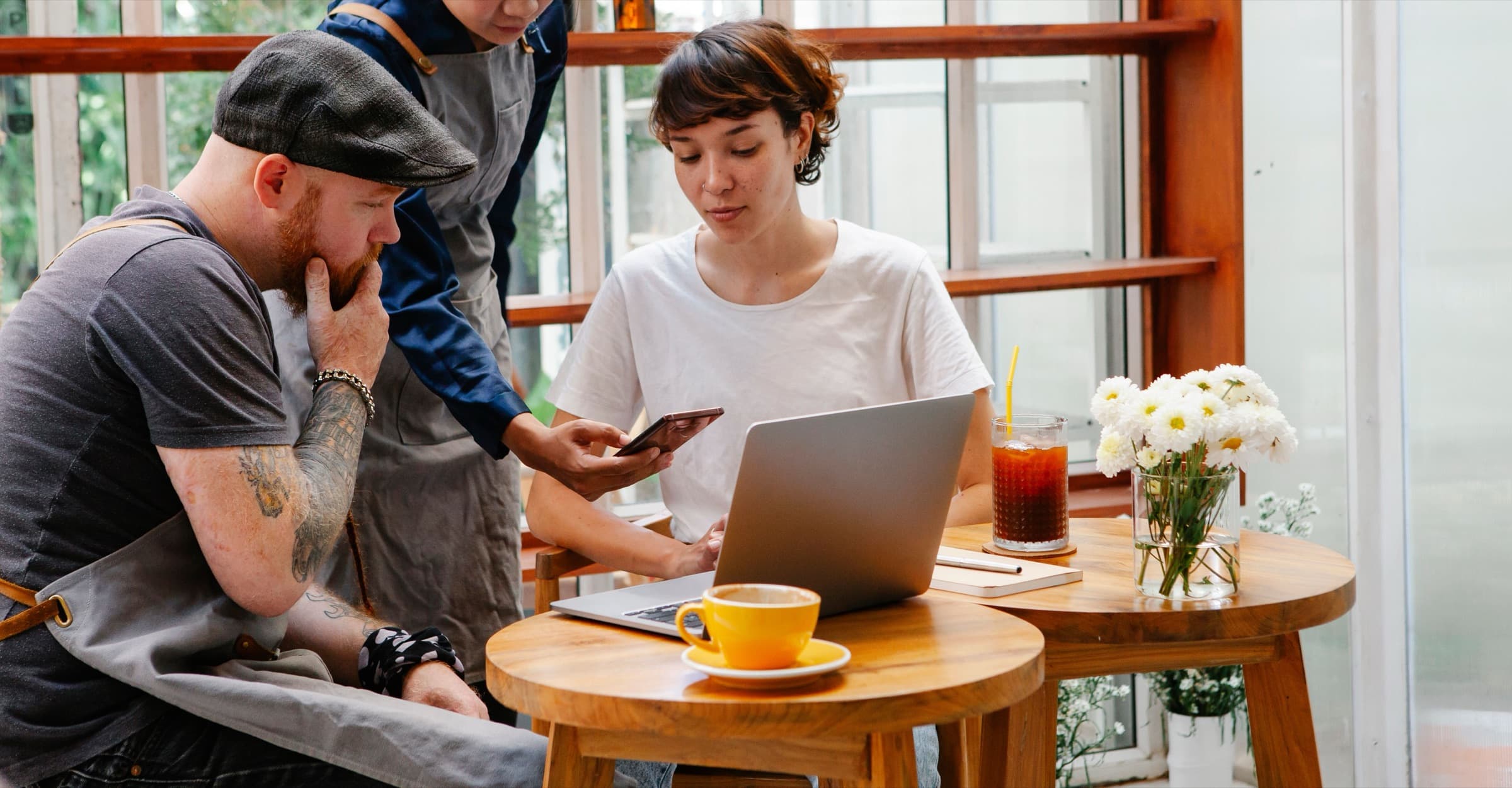 A café owner going through something on a laptop with two of her staff.